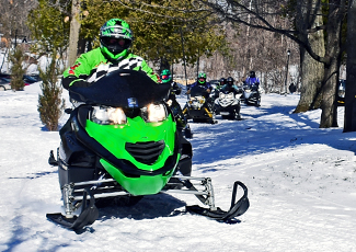 Four Snowmobilers riding along a trail